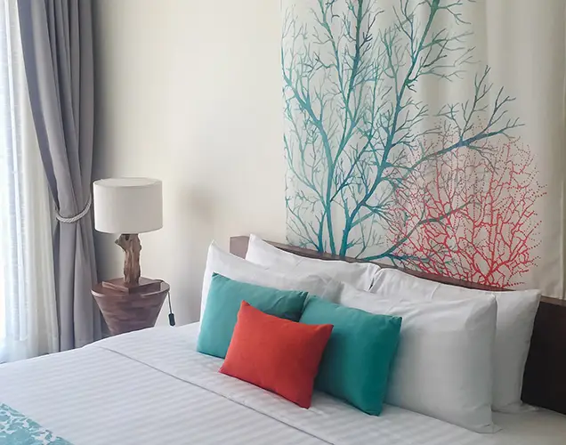 A bright, modern bedroom at Surfing Life with white linen, turquoise cushions and coral artwork