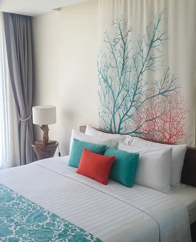 A bright, modern bedroom at Surfing Life with white linen, turquoise cushions and coral artwork